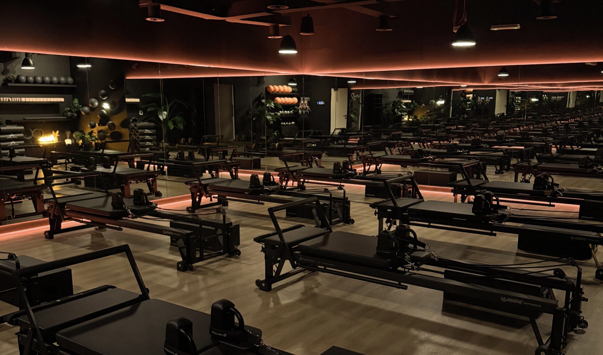 The dark reformer room at Pure Motion, rows of Merrithew machines under the ember glow
